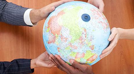 A group of students have their hands on a globe.