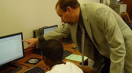An instructor is guiding an accounting student who is using a computer.