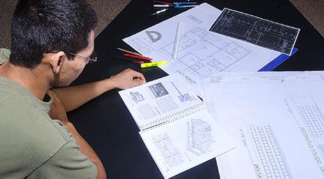 A student is examining blueprints and 建设 documents.